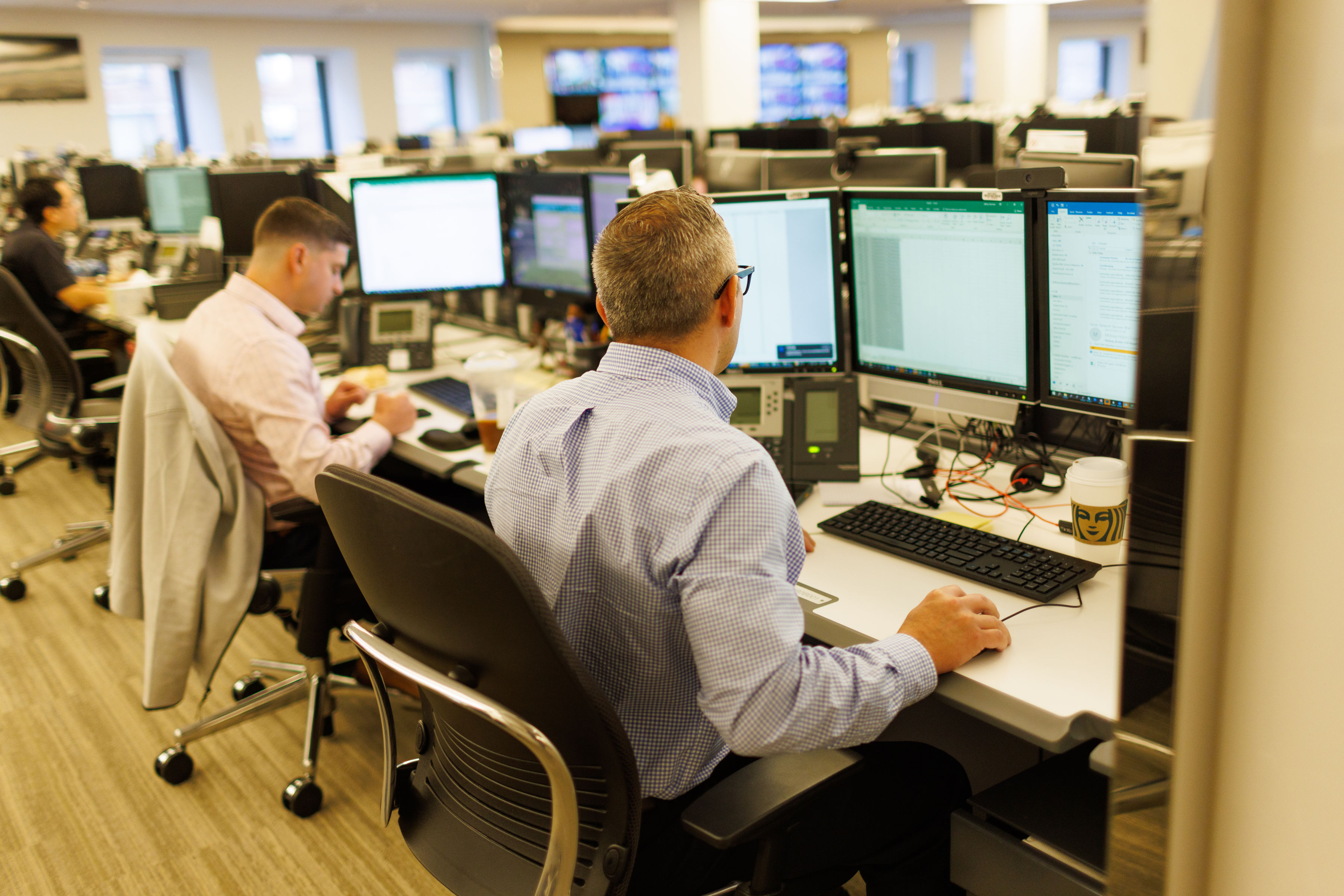 Two men in an office in front of screens